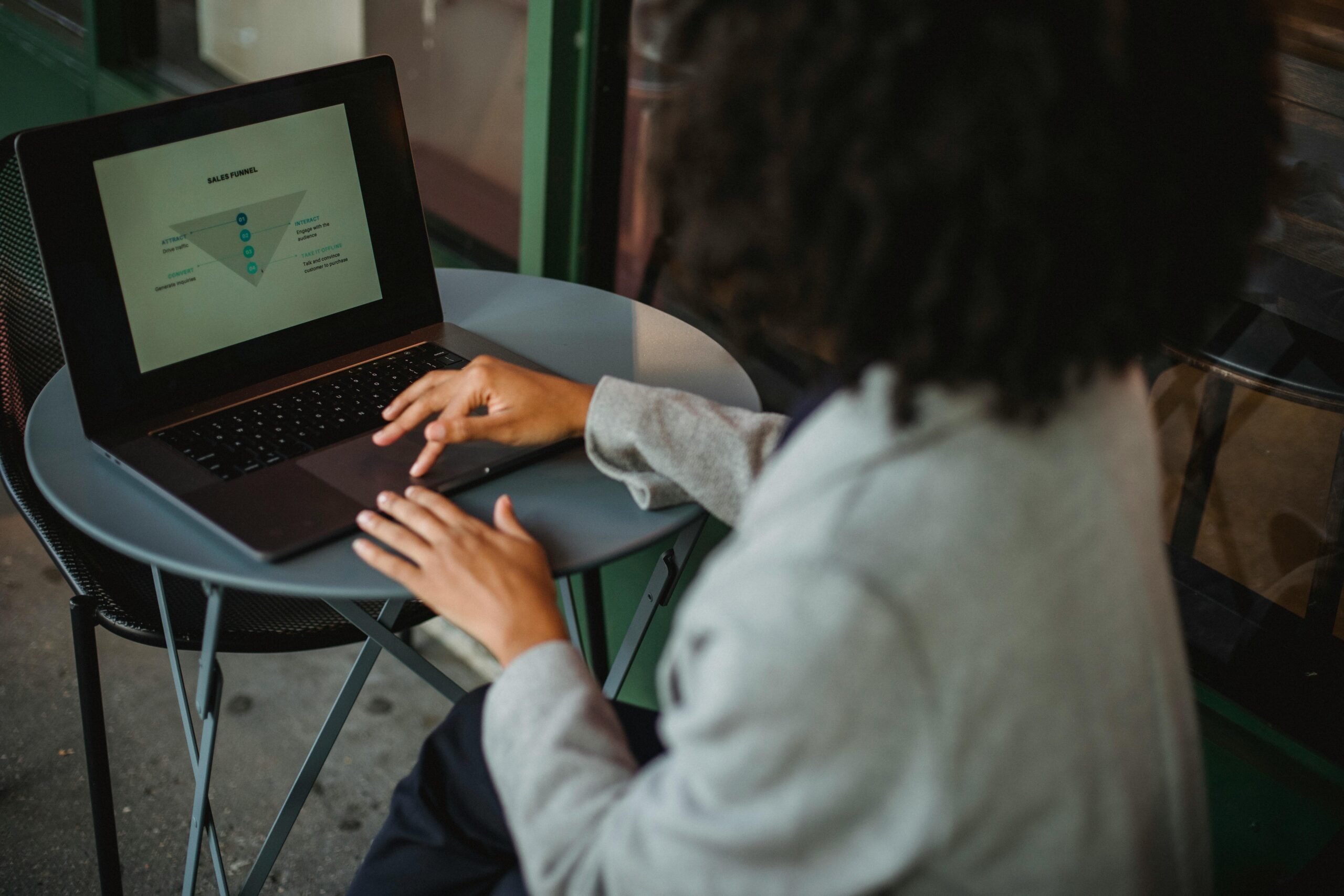 Unrecognizable ethnic woman analyzing diagram on laptop